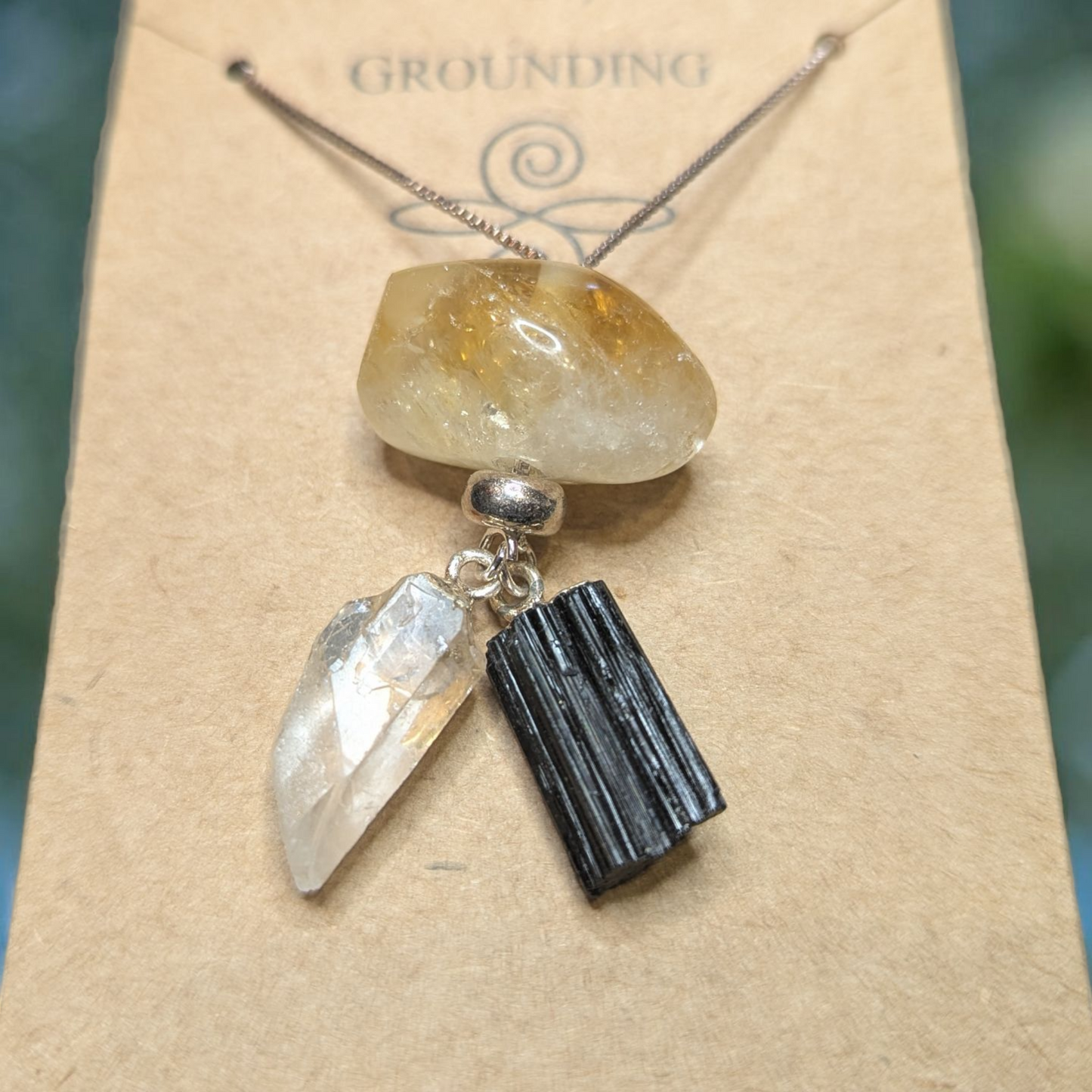 Close-up view of Citrine, Clear Quartz, and Black Tourmaline crystal pendants on grounding necklace.