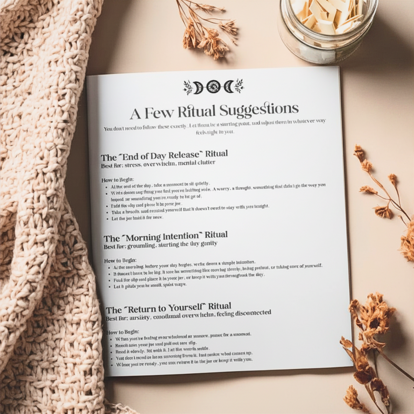 Open book with ritual suggestions on a textured surface with dried flowers and a candle.